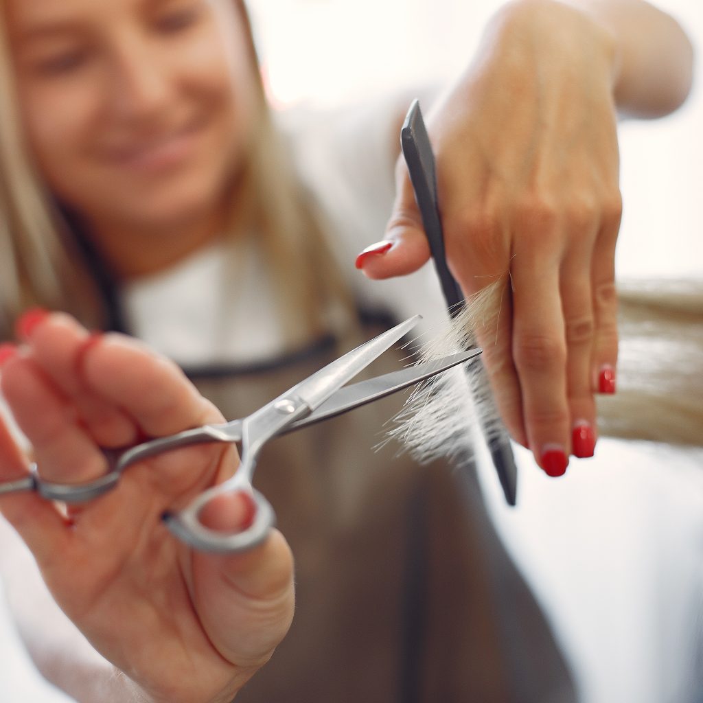 Hairdresser cut hair her client. Woman in a hair salon